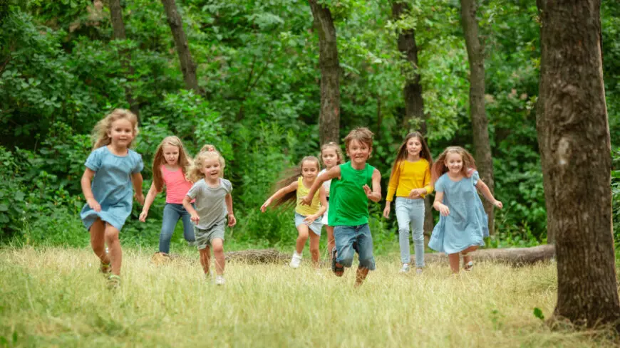 Kids, children running on green meadow, forest. Childhood and summertime