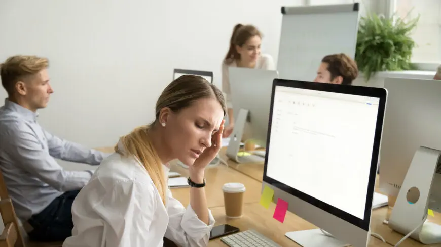 Exhausted female employee suffering from headache touching templ